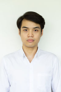 Portrait of young man standing against white background