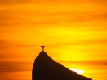 Silhouette cross against sky during sunset