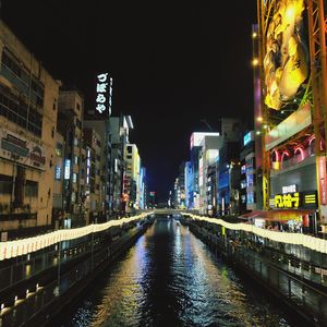 Illuminated bridge over canal amidst buildings in city at night