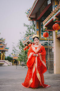 Portrait of young woman standing with red umbrella