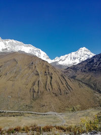 Scenic view of snowcapped mountains against clear blue sky