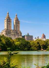 Buildings by river against clear blue sky