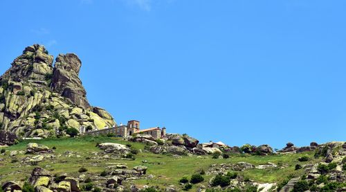 Scenic view of rock formation and monastery against clear blue sky