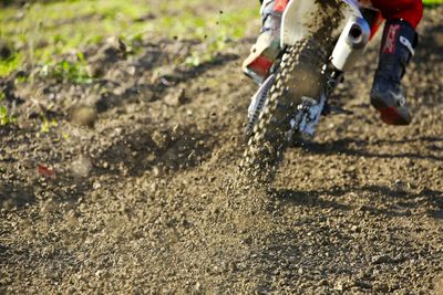 Low section of man riding motorcycle on mud