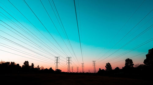 Silhouette of pylons against sky during sunset