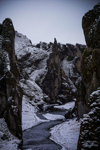 Low angle view of rocks against clear sky during winter