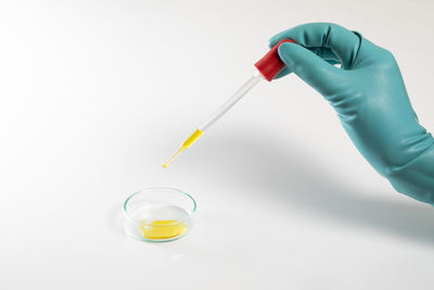 Close-up of hand holding glass over white background