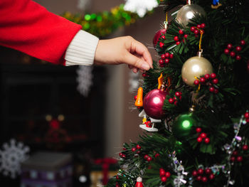 Cropped image of hand decorating christmas tree