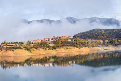 Typical residential buildings located on hill above calm river in scenic mountainous valley on sunny autumn day in riano
