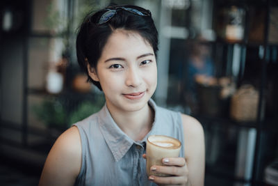 Portrait of young woman drinking coffee in cafe