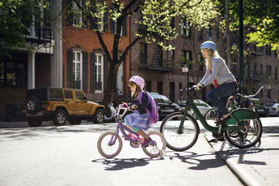 Mother and daughter riding bicycles on street