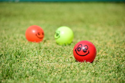 Close-up of red ball on grass with a happy face