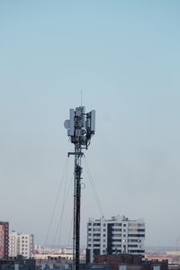 Low angle view of crane by building against clear sky