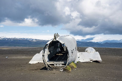 Broken airplane wreck at black sand beach in solheimasandur against cloudy sky