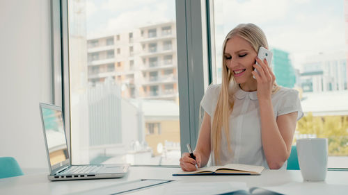 Woman talking on smart phone at office