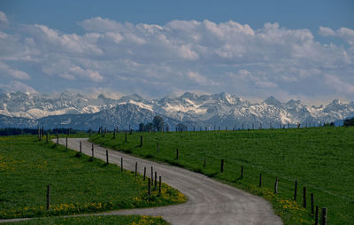 Road by agricultural field against sky