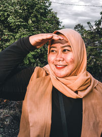 Portrait of smiling woman standing against trees