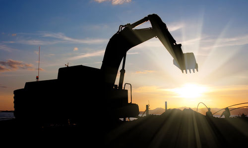 Silhouette of construction site against sky during sunset