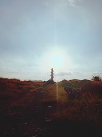 Lighthouse on rock formation against sky during sunset