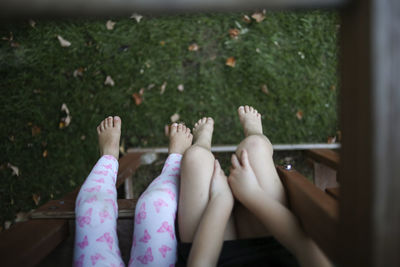 Low section of sisters sitting on outdoor play equipment at playground
