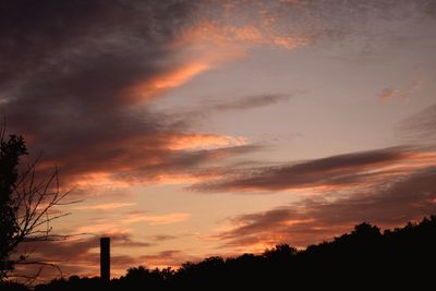 Low angle view of silhouette trees against dramatic sky