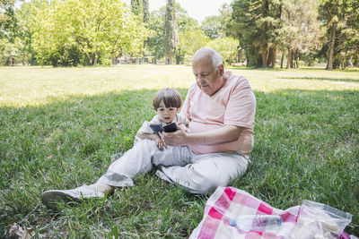 Boy with grandfather using smart phone at park