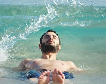 Shirtless man swimming in sea