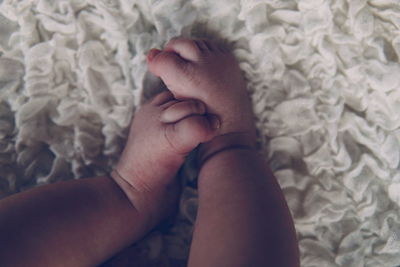 Low section of baby lying on bed