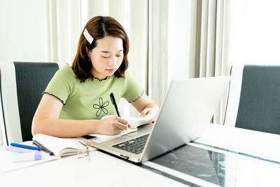 Young woman using phone while sitting on table