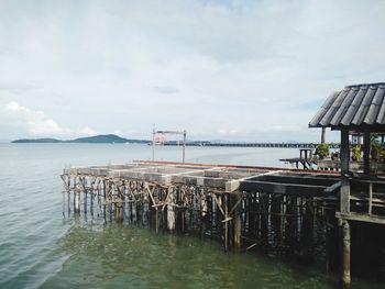 Pier on sea against cloudy sky