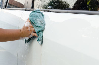 Cropped hand of woman washing car