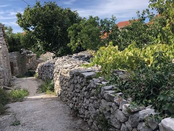 Stone wall by trees against sky