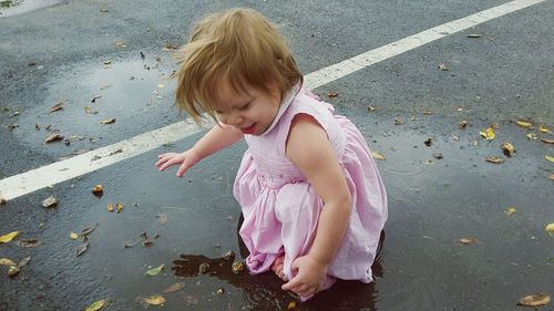 Cute baby playing in puddle on road