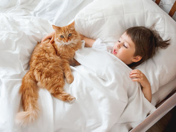 High angle view boy lying on bed with cat