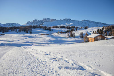 Snow covered landscape against clear blue sky