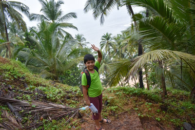 Full length of boy standing on palm tree