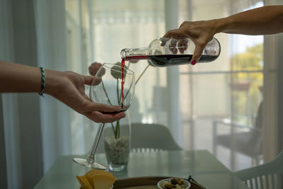 A men serves red wine to a woman in a glass for red wine.