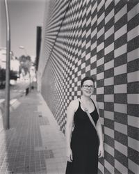 Portrait of smiling woman standing against wall