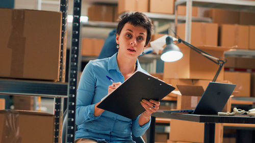 Portrait of young woman standing against building