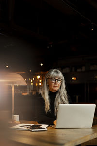 Woman using mobile phone while sitting on table