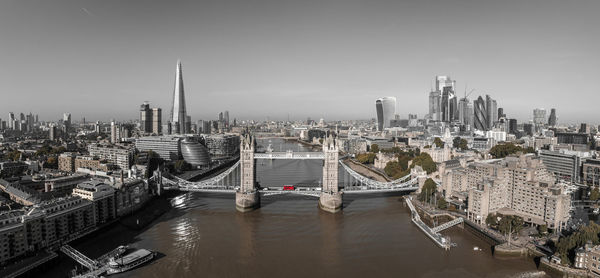 Beautiful black and white photo of london tower bridge with an iconic red bus driving on it.