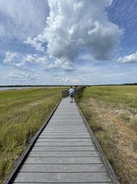 Boardwalk amidst field against sky