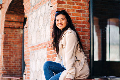 Portrait of beautiful woman against brick wall