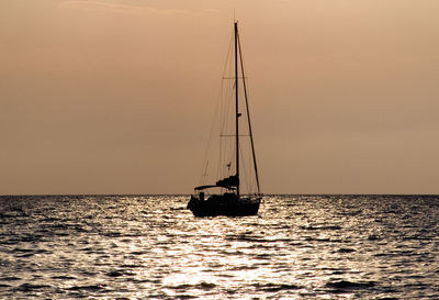 Silhouette sailboat sailing on sea against sky during sunset