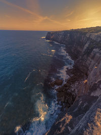 Scenic view of sea and cliff against sky
