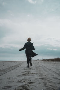 Rear view of man on beach against sky