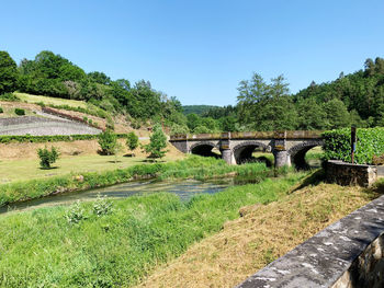 Arch bridge on field against clear sky
