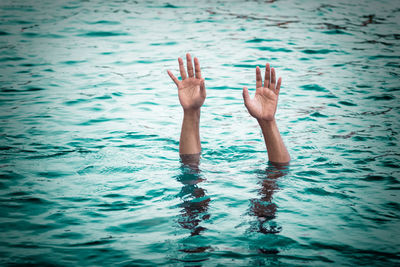 Cropped image of person with arms raised in sea