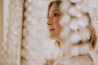 Young female in victorian shirt sitting in giant crystal chandelier and smile