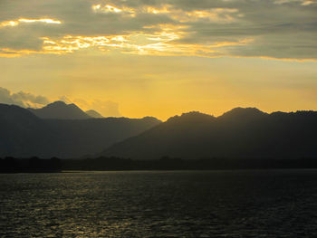 Scenic view of sea and mountains against sky during sunset